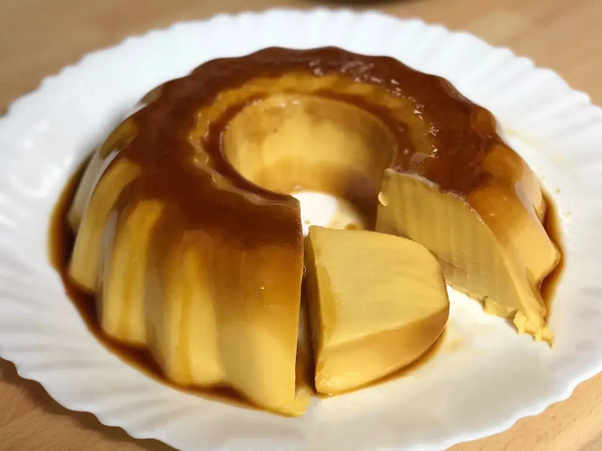 Delicioso flan de chocolate blanco con caramelo líquido, servido en un plato blanco.