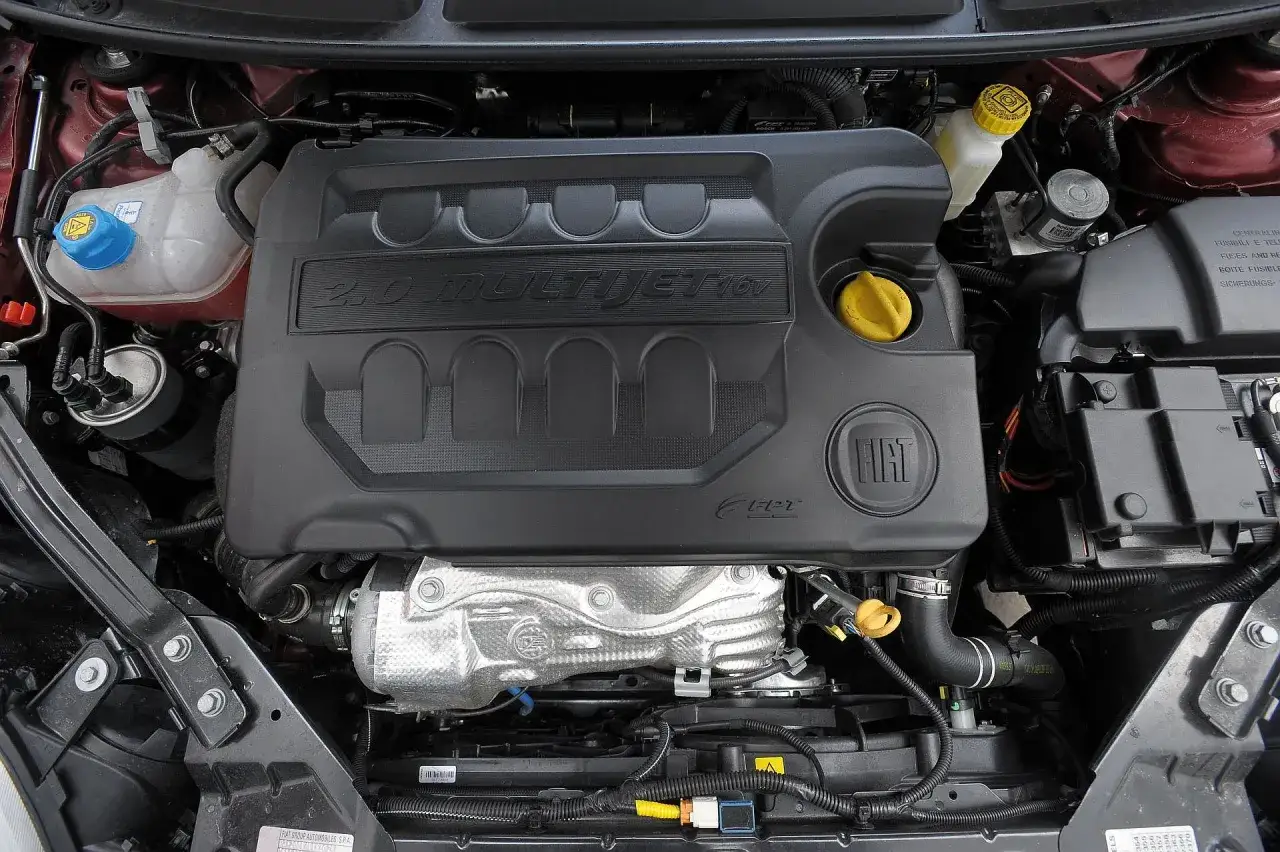 Silnik 2.0 MultiJet w Fiat Bravo 2011. Widoczny czarny plastikowy kolektor dolotowy z logo Fiat.