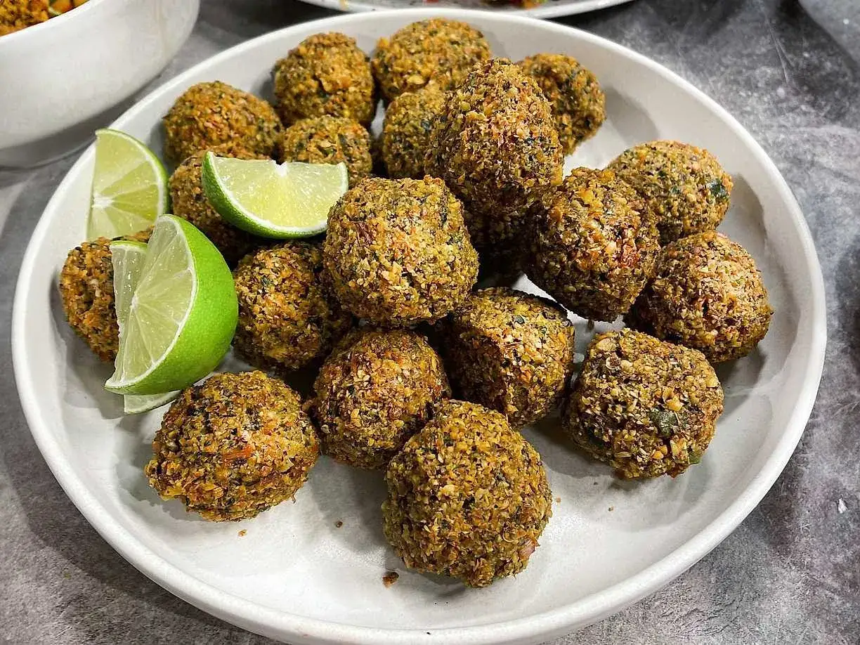 En tallrik med gyllene falafelbollar, perfekt f&ouml;r ett gott falafel recept. Garnerad med f&auml;rska limeklyftor.
