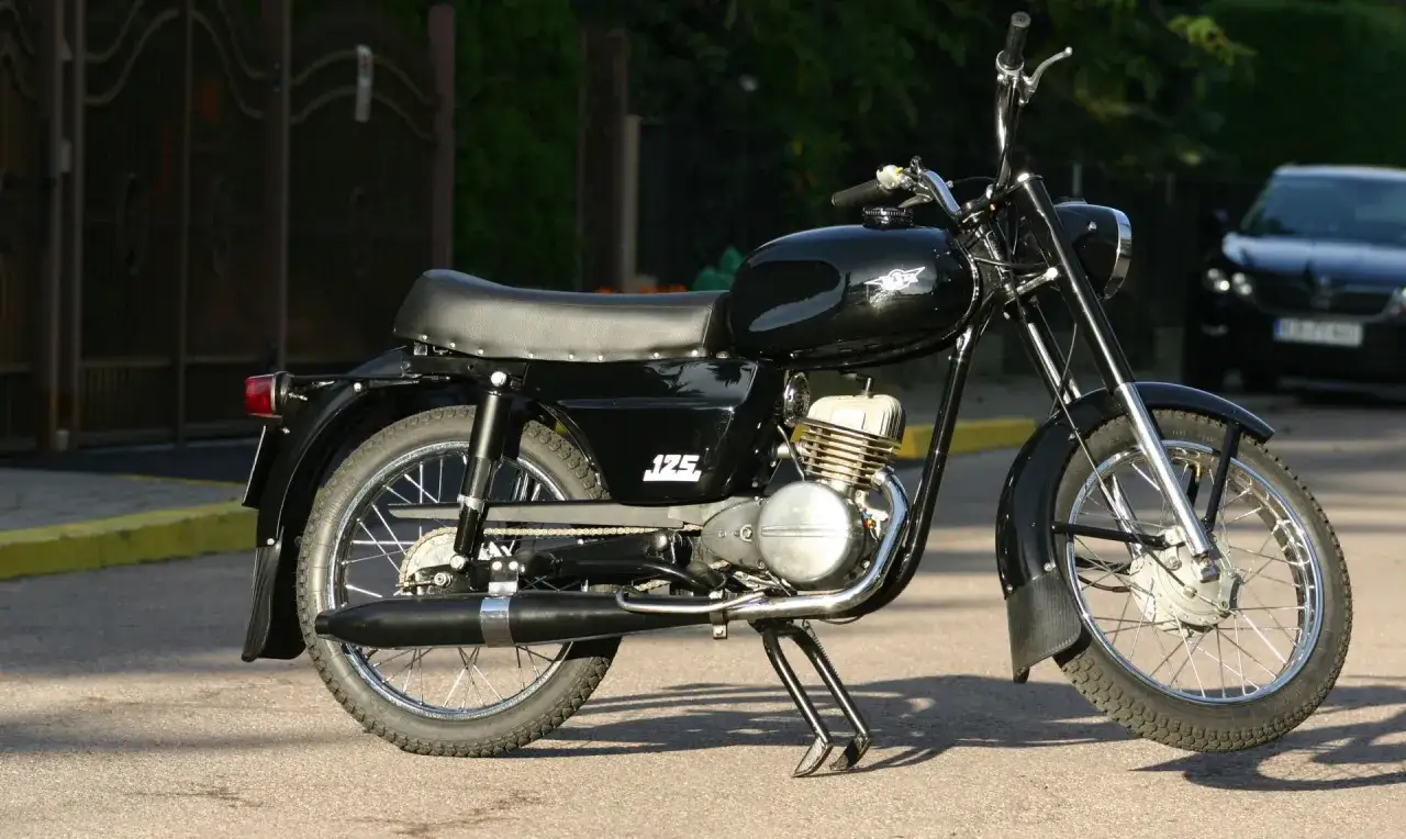 Czarny motocykl WSK 125 z lat 70. na postoju, gotowy do jazdy.