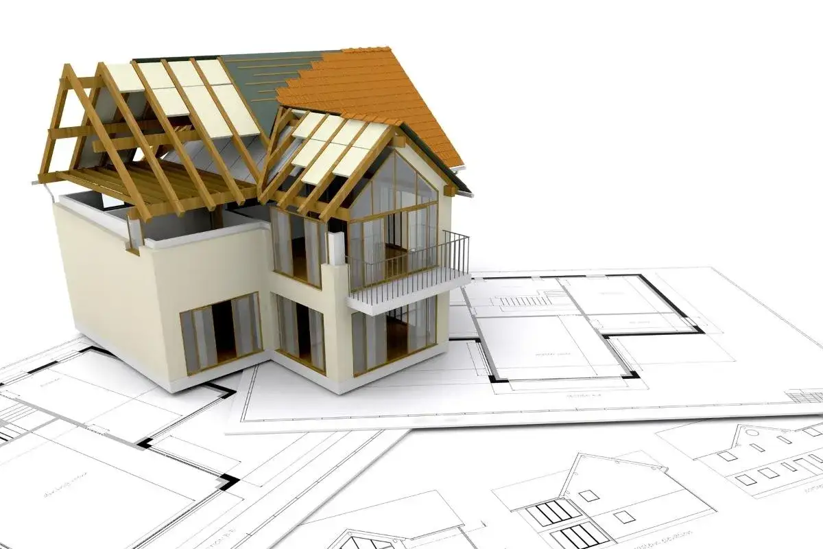 Model domu w budowie na planach architektonicznych, symbolizujący transzę kredytu hipotecznego na budowę.