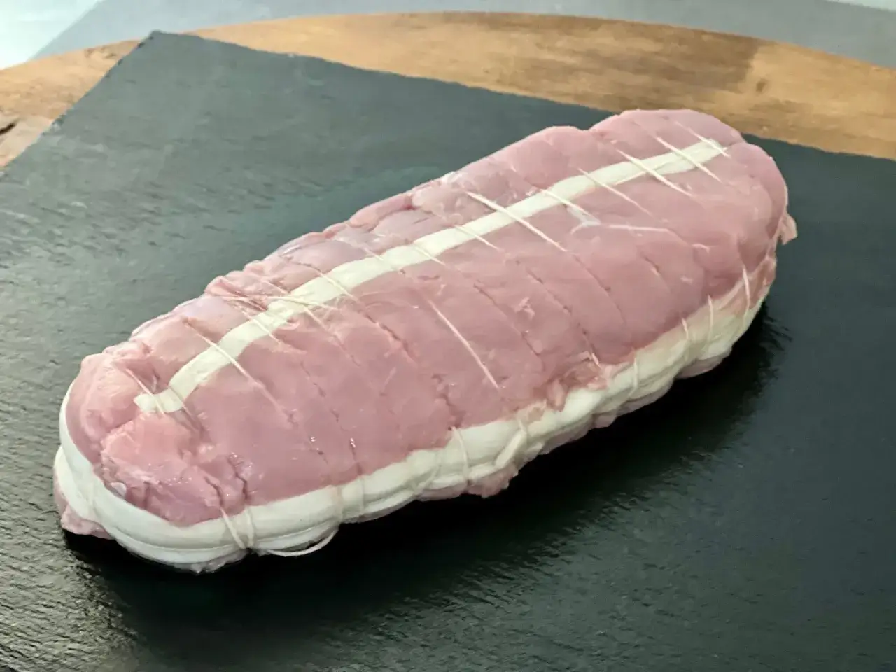 Un rôti de veau cru, ficelé avec soin, prêt à être cuisiné pour un repas savoureux.