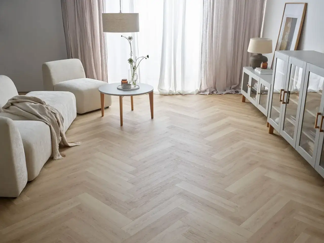 Jasna jodełka na podłodze salonu, tworząca przytulną atmosferę.