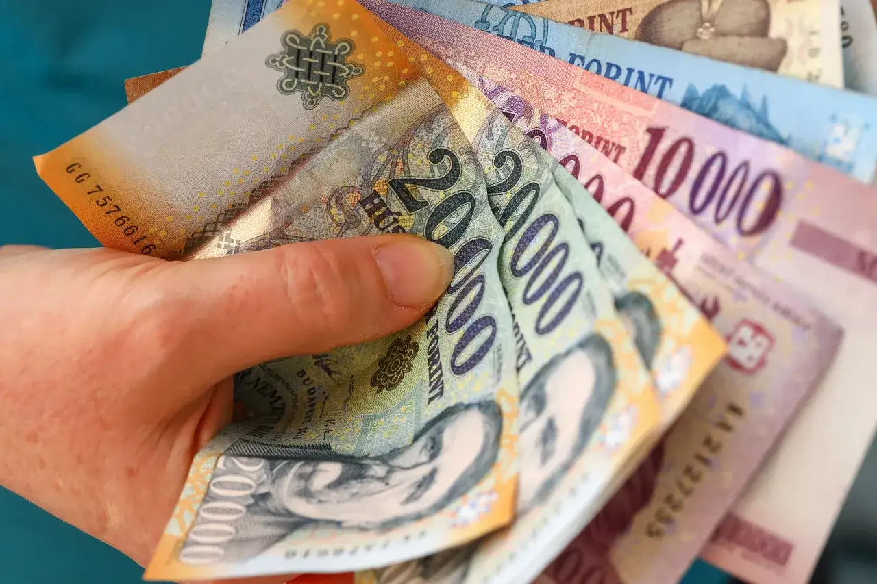 Węgry używają forintów, więc nie można tam płacić euro. Dłoń trzyma stos węgierskich banknotów.