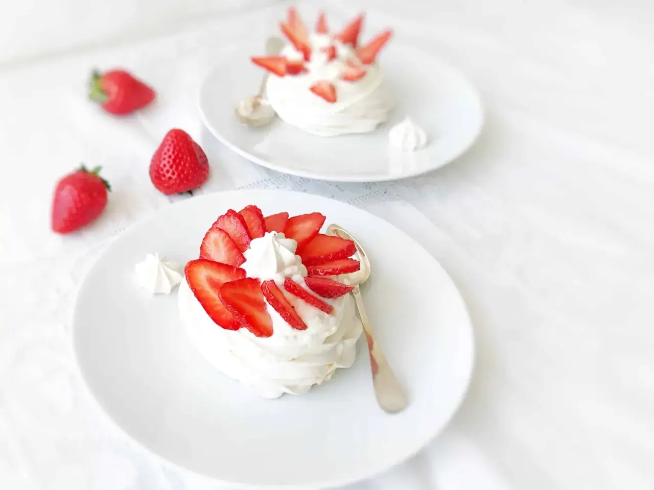 Deux pavlovas individuels garnis de cr&egrave;me fouett&eacute;e et de fraises fra&icirc;ches, pr&ecirc;ts &agrave; &ecirc;tre d&eacute;gust&eacute;s. Une recette pavlova simple et d&eacute;licieuse.