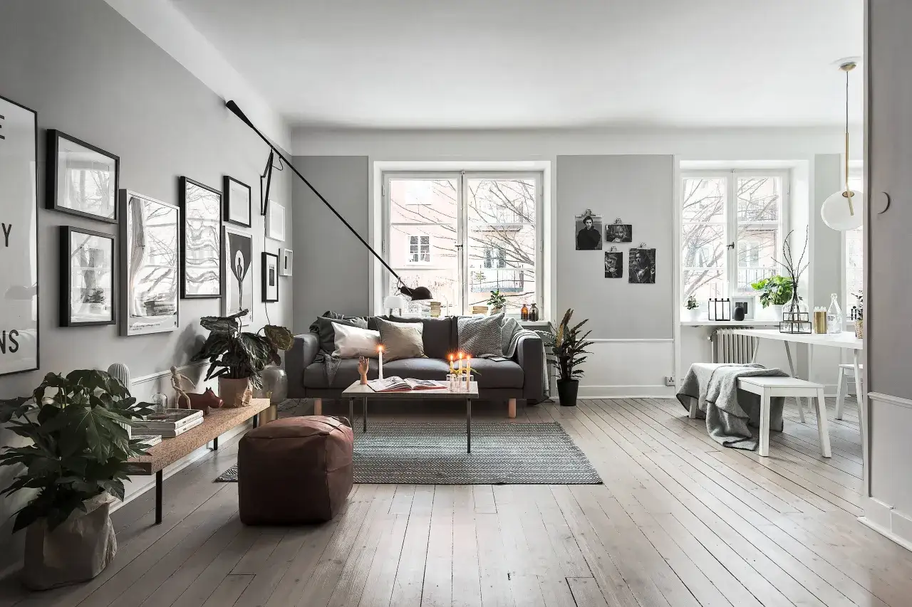 Ett stilrent vardagsrum med grå soffa, kaffebord med ljus och en bänk som styla sideboard.