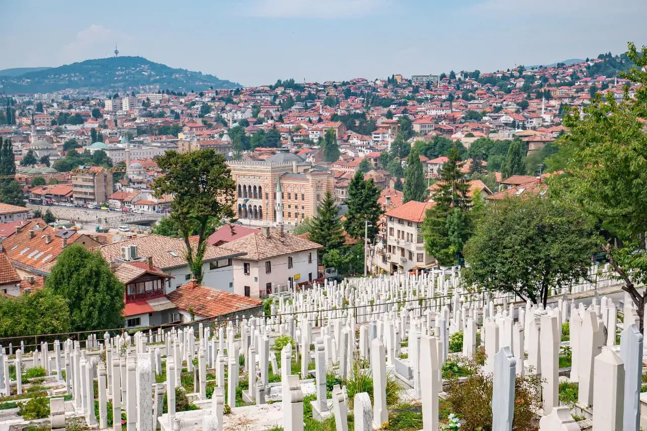 Widok na cmentarz z białymi nagrobkami i panoramę Sarajewa. Warto zobaczyć to miasto!