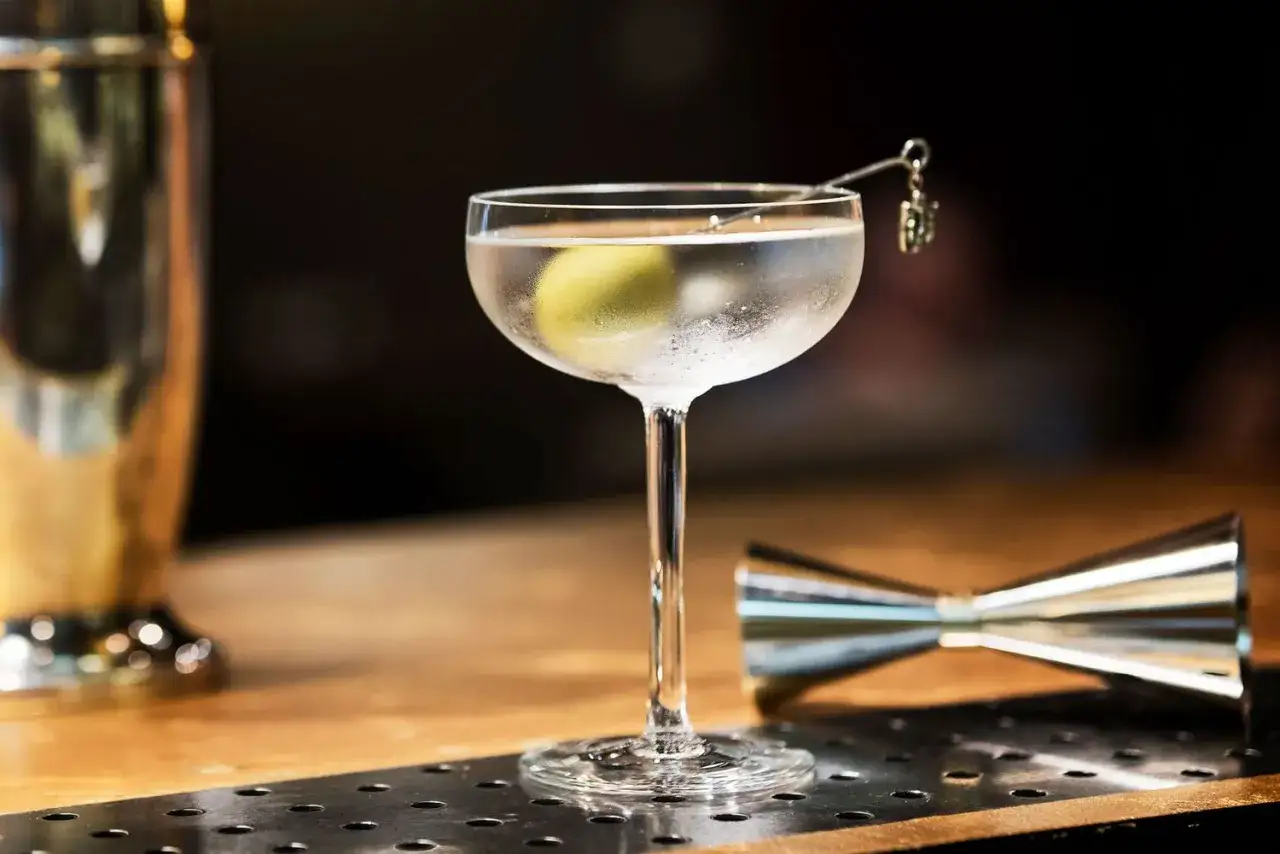 Eleganckie drinki z ginem na barze. Schłodzony martini z oliwką, obok shaker i jigger.