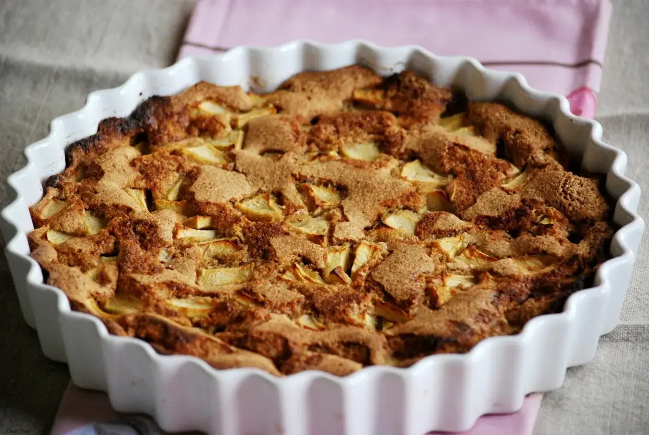 Tarta de manzana casera reci&eacute;n horneada, con trozos de manzana visibles bajo una cobertura dorada y crujiente.