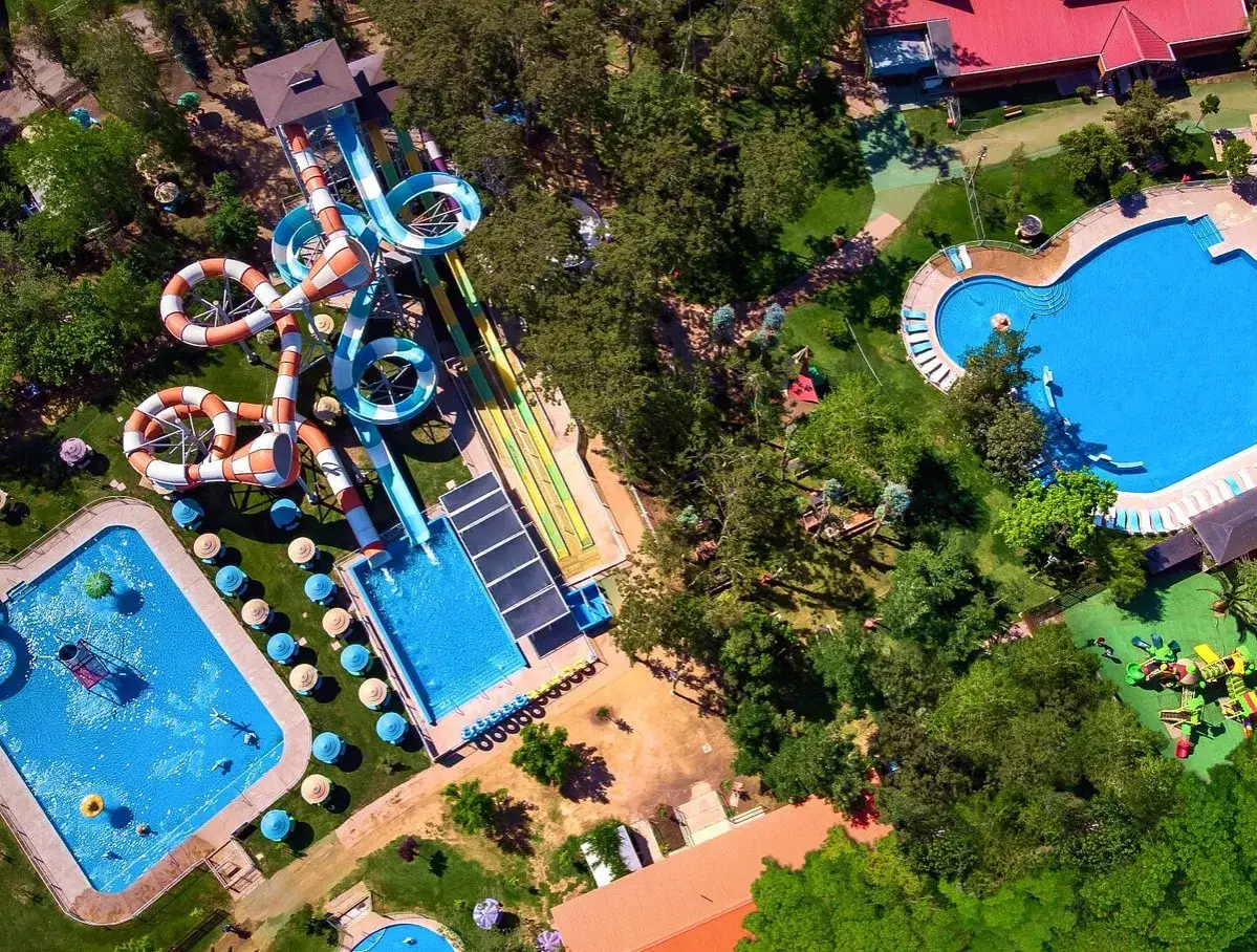 Widok z lotu ptaka na Santiago Aquapark z kolorowymi zjeżdżalniami, basenami i zielenią.