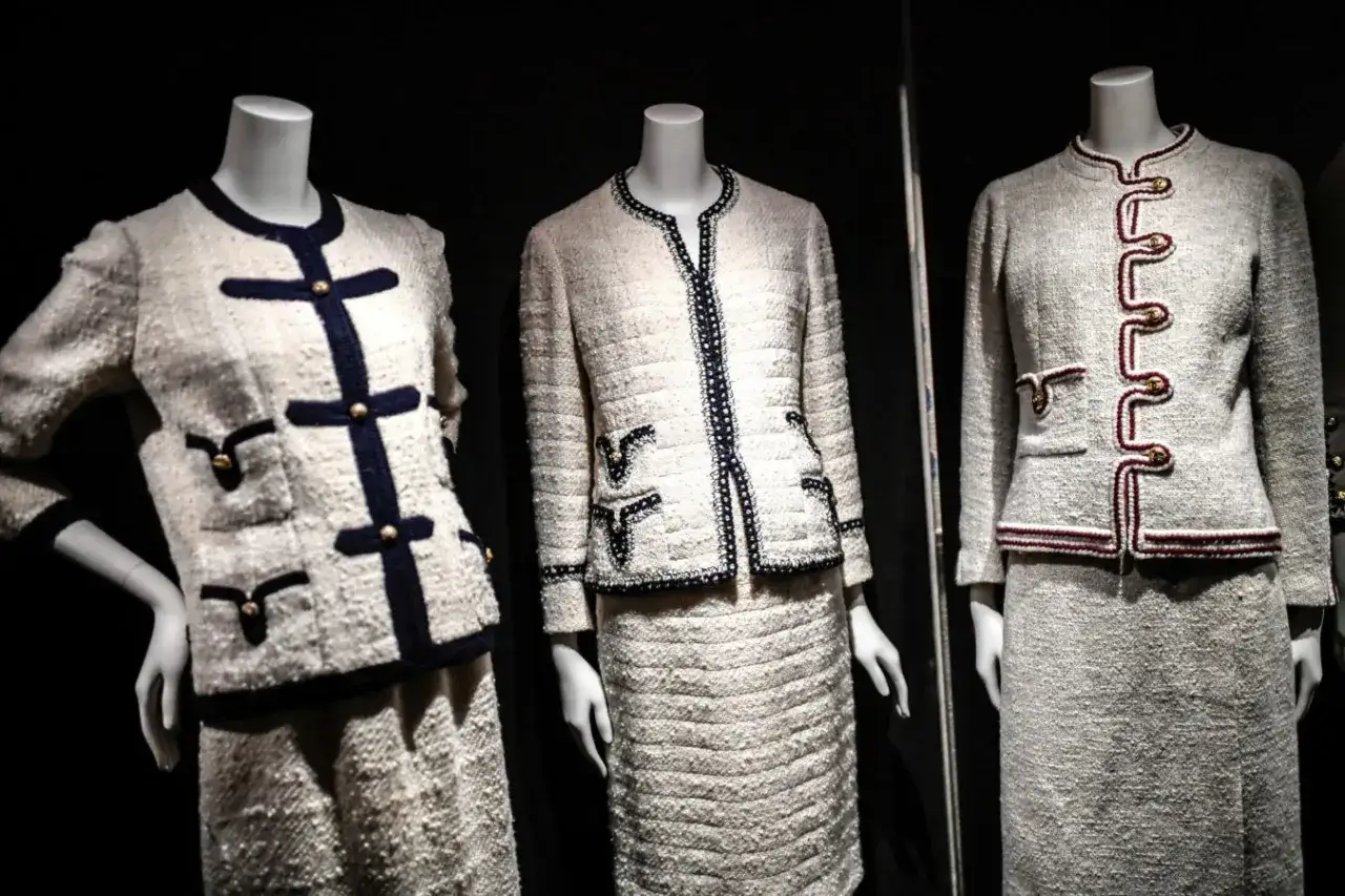 Tre iconici tailleur in tweed, un inconfondibile stile Chanel, con dettagli in blu navy e oro.