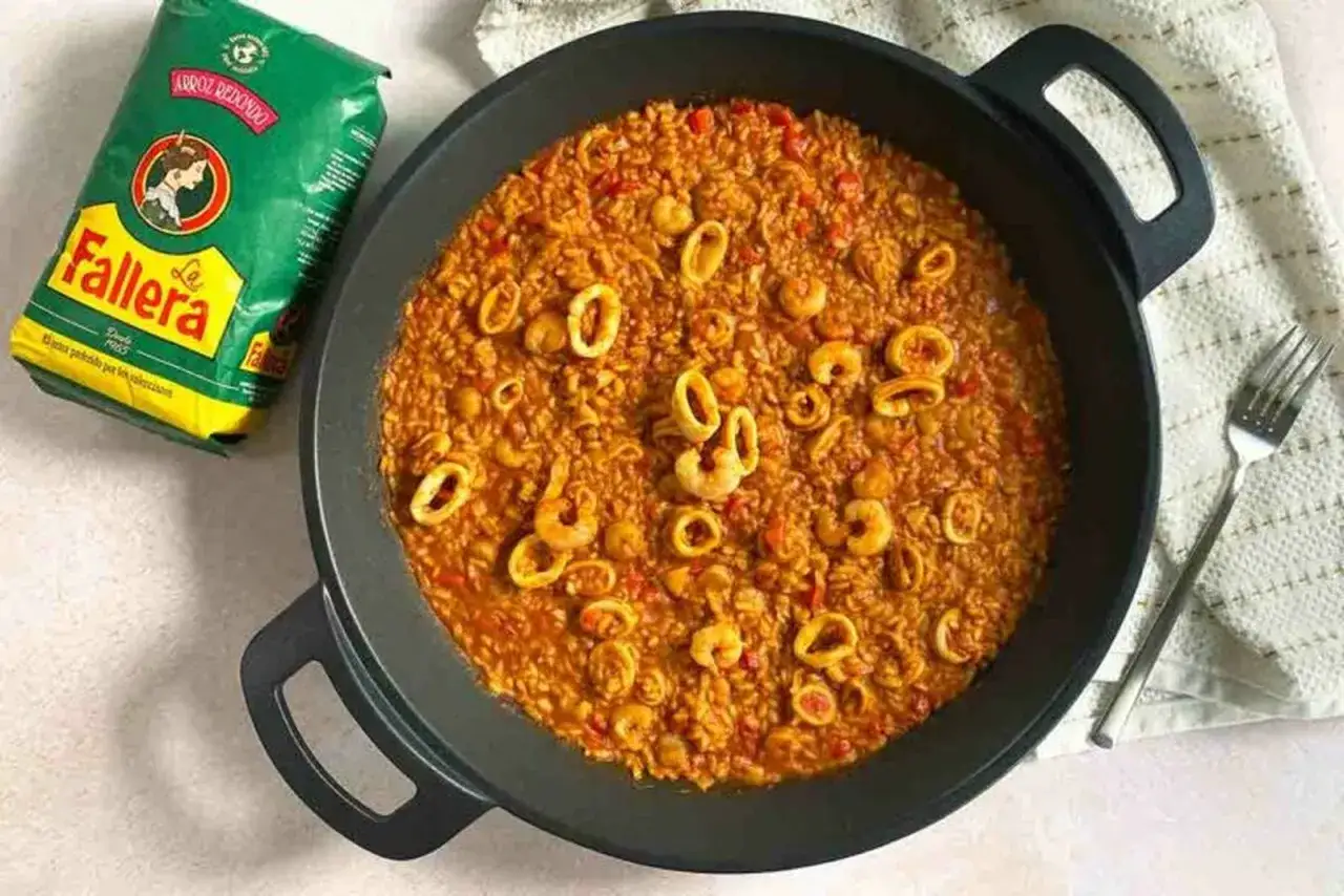 Arroz con calamares y gambas en paellera, junto a un paquete de arroz Fallera. ¡Un plato delicioso!
