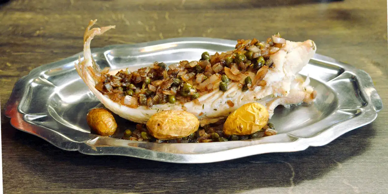 Poisson blanc garni d'oignons et câpres, servi avec des pommes de terre. Un plat classique de raie au beurre noir.