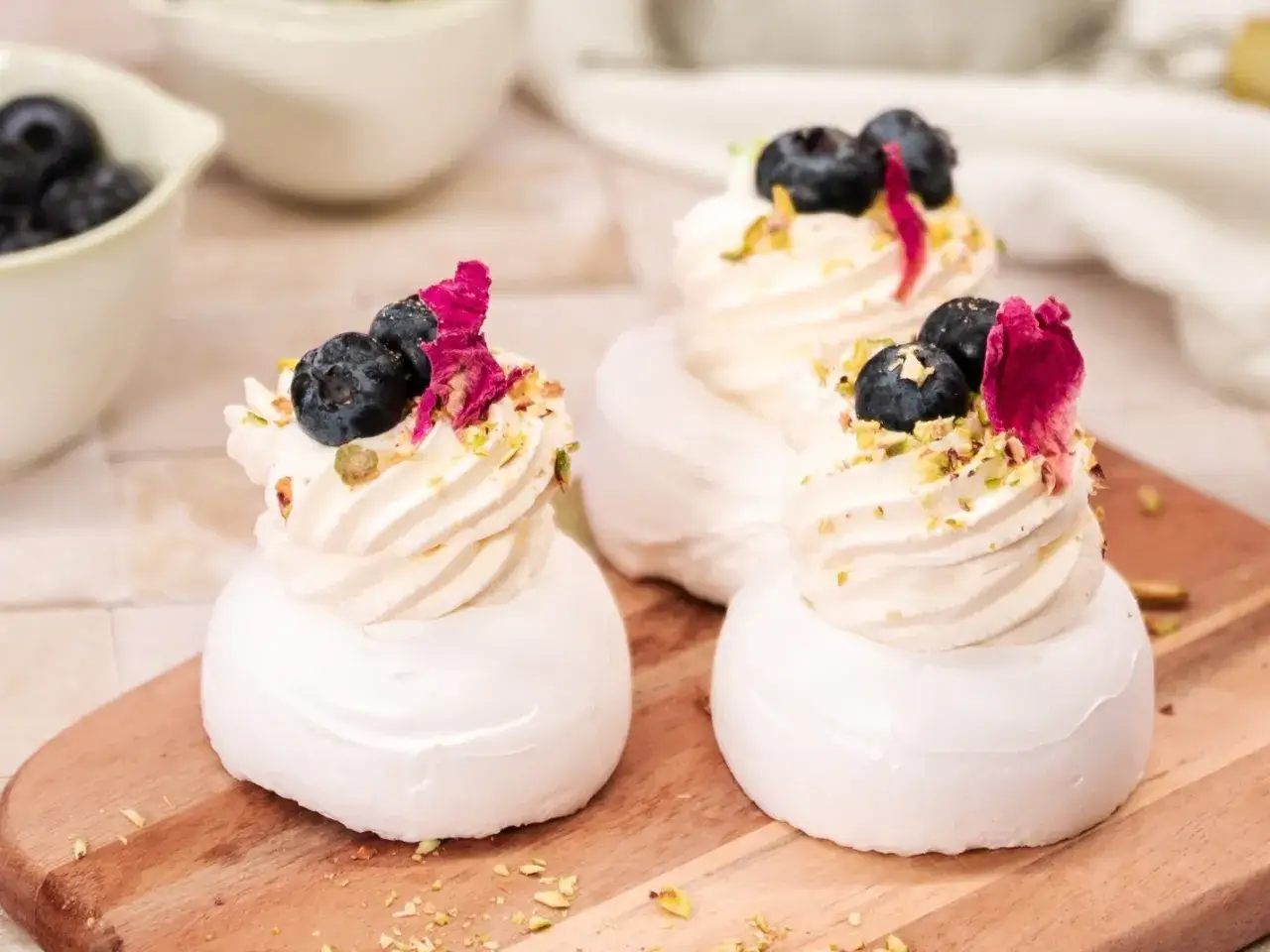 Mini pavlova z bitą śmietaną, bor&oacute;wkami i płatkami r&oacute;ży. Pyszna, lekka i idealna na deser.