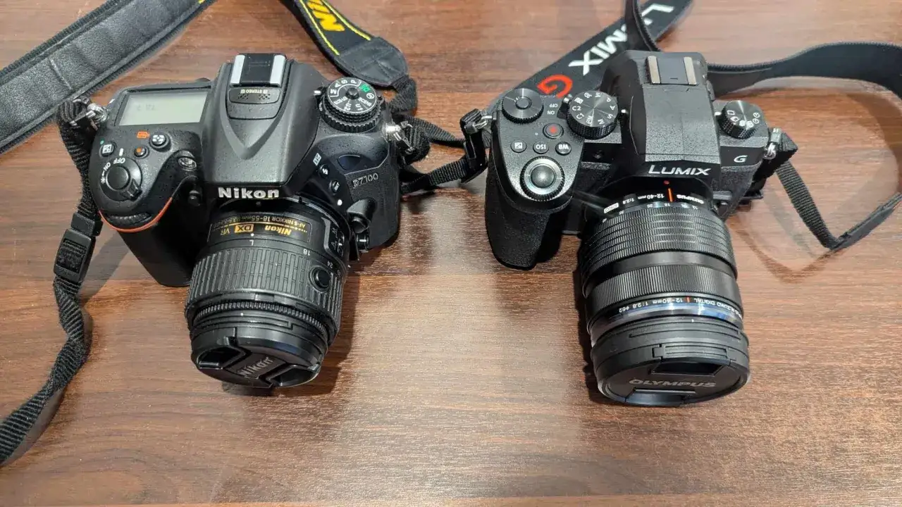 Due fotocamere, una Nikon e una Lumix, con obiettivi montati. La Nikon ha un mirino elettronico visibile.