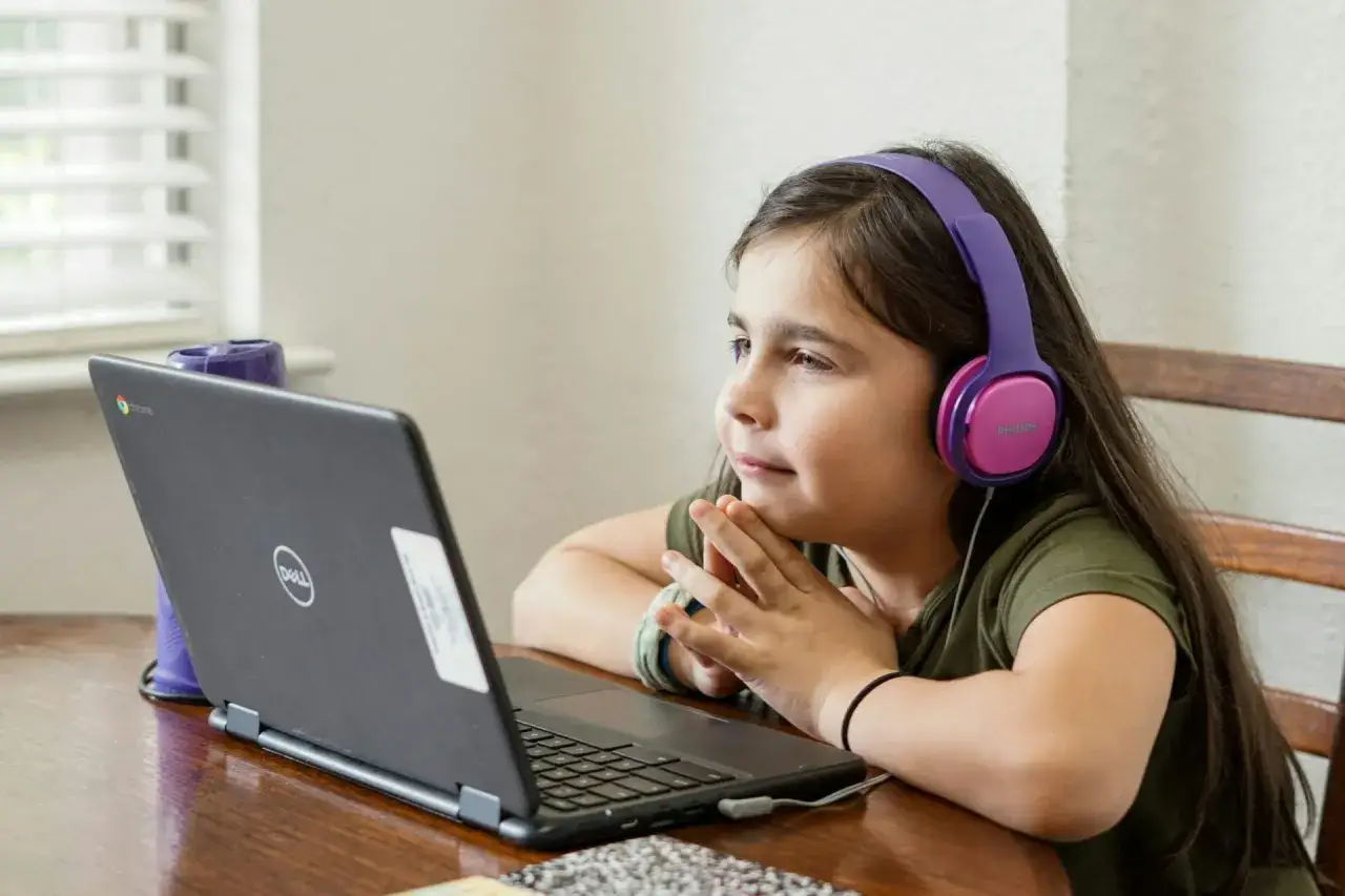 Dziewczynka w słuchawkach słucha **spotify audiobooki dla dzieci** na laptopie.