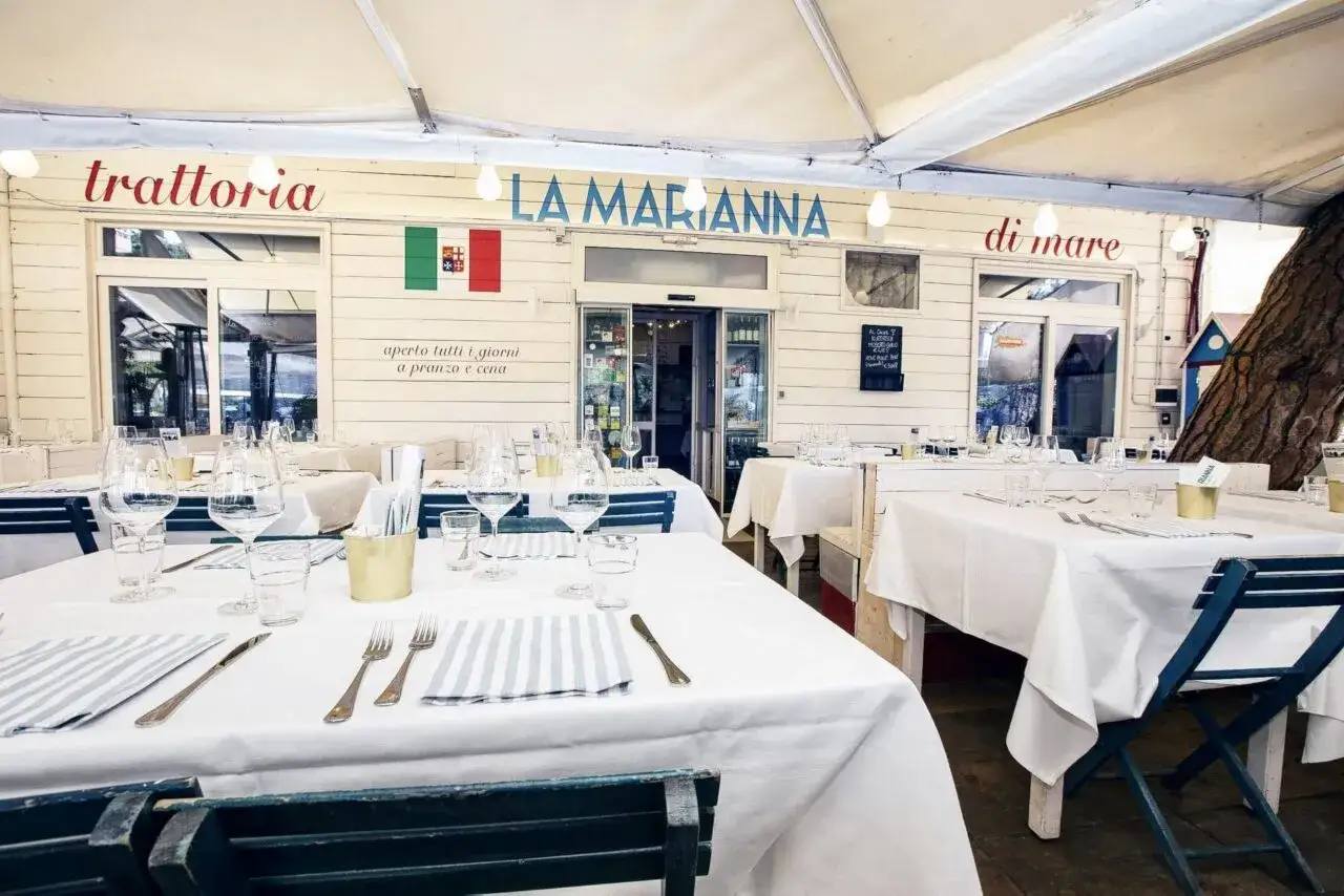 Trattoria La Marianna, un ristorante di pesce nella città di Rimini, con tavoli apparecchiati all'esterno sotto una tettoia.