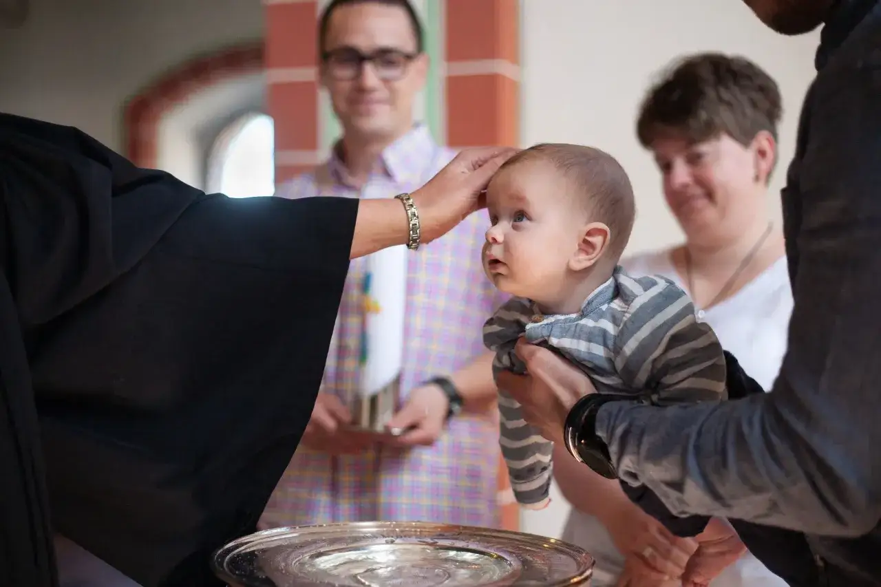 Taufe eines Babys. Die Frage, wie viele Paten man haben darf, ist hier nicht relevant, da die Familie im Vordergrund steht.