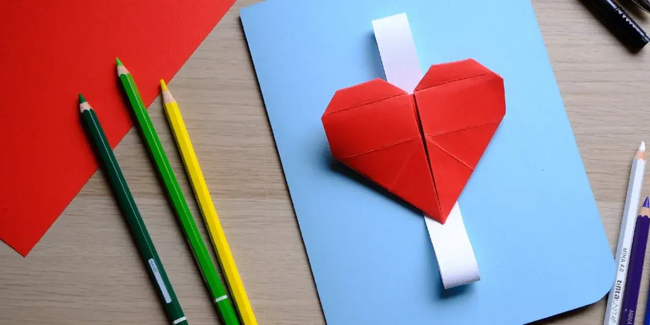 Cuori di carta rossi, matite colorate e fogli per un lavoretto per la festa dei nonni.