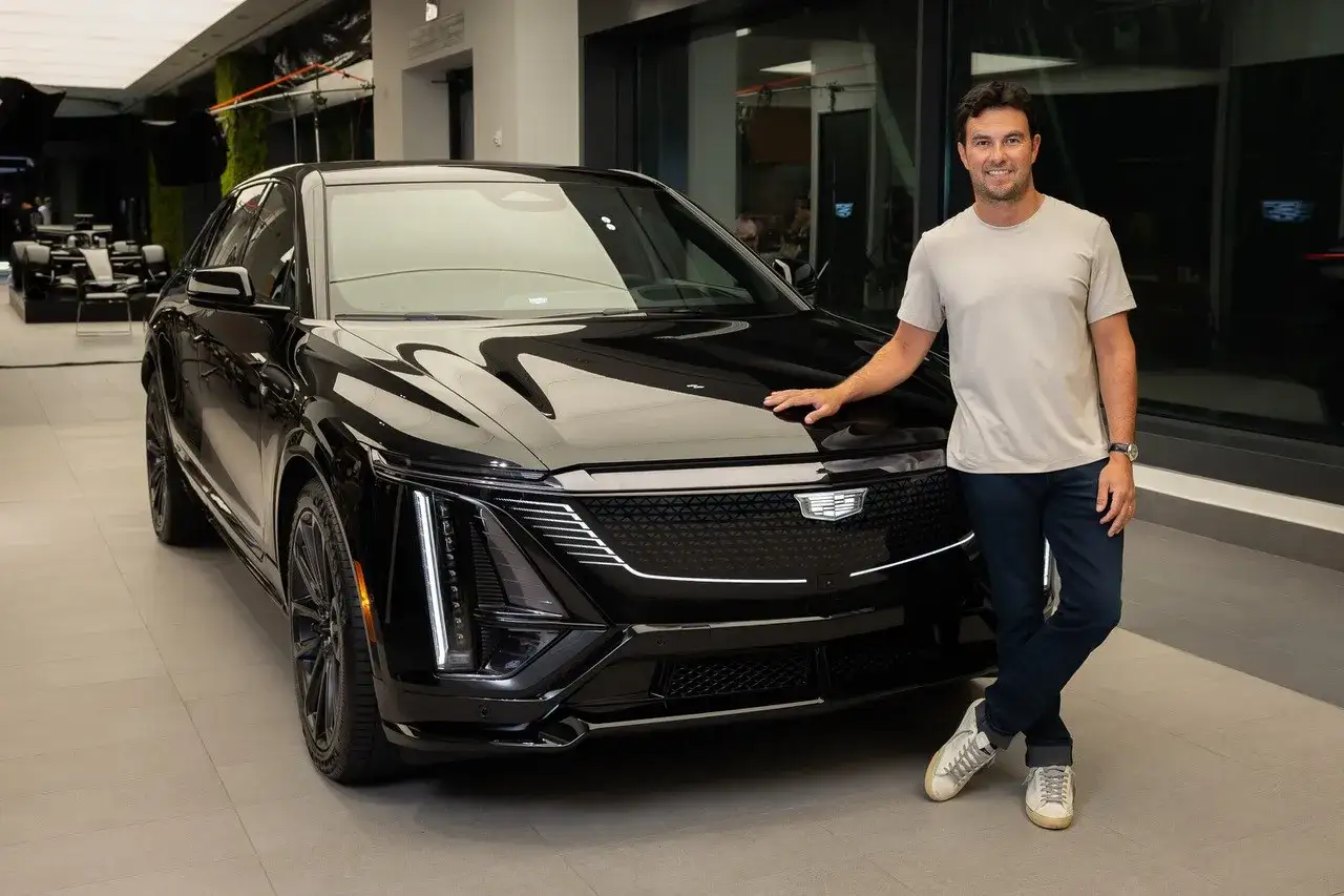 Checo P&eacute;rez posa junto a un elegante Cadillac negro, mostrando su estilo y afinidad por los autos de lujo.