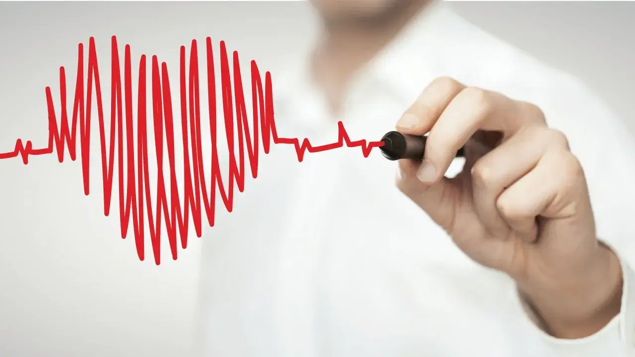 Dłoń rysuje markerem czerwoną linię EKG, symbolizującą szybki, wysoki puls.