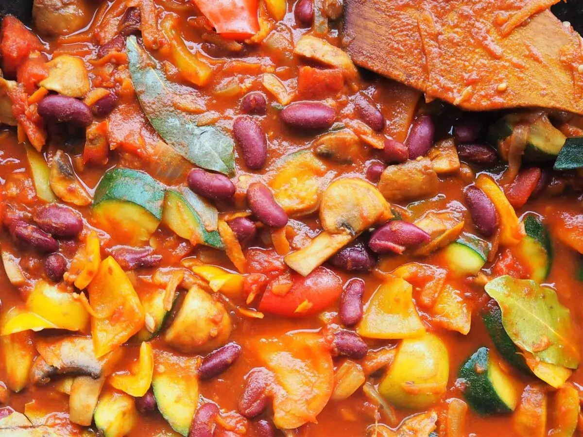 Gulasz z fasolą, pełen warzyw: cukinii, papryki, pieczarek i pomidorów, gotuje się w aromatycznym sosie.
