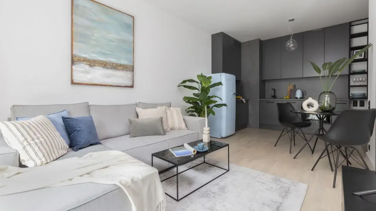 Przytulny salon z aneksem kuchennym 22m2. Jasna kanapa, błękitna lodówka i nowoczesna kuchnia tworzą stylową przestrzeń.