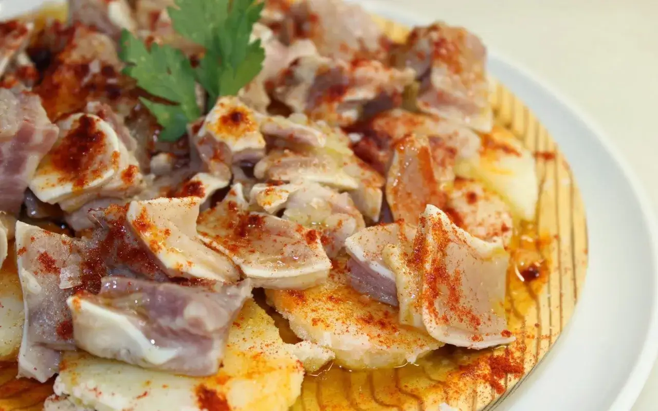 Oreja a la gallega, trozos de oreja de cerdo cocida, aderezada con pimentón y aceite, servida sobre patatas.