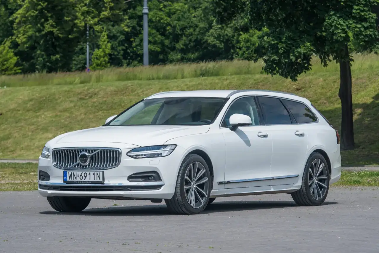 Białe Volvo V90 na tle zieleni. Poznaj jego dane techniczne i możliwości.