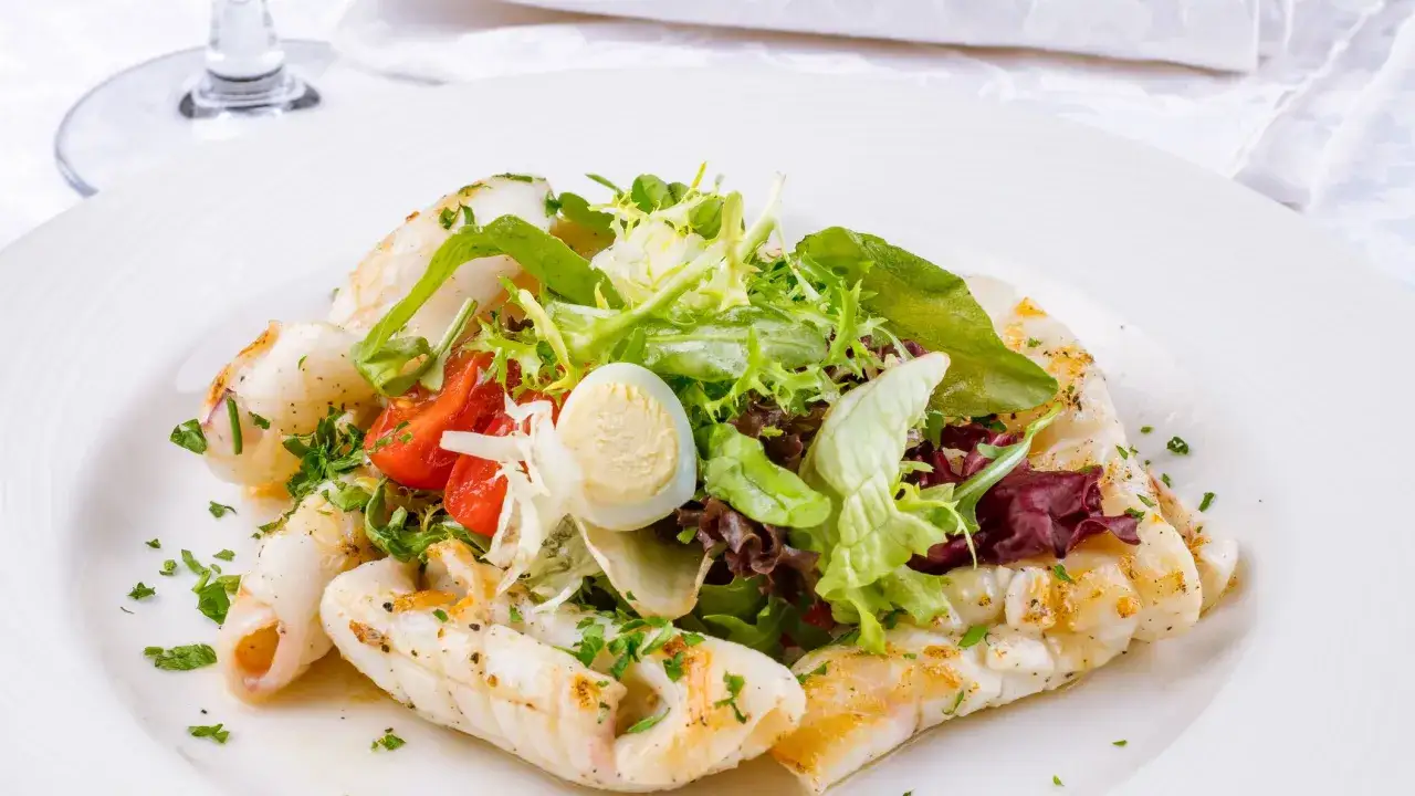 Deliziosa insalata di seppie grigliate con pomodorini, uovo di quaglia e un mix di insalate fresche.