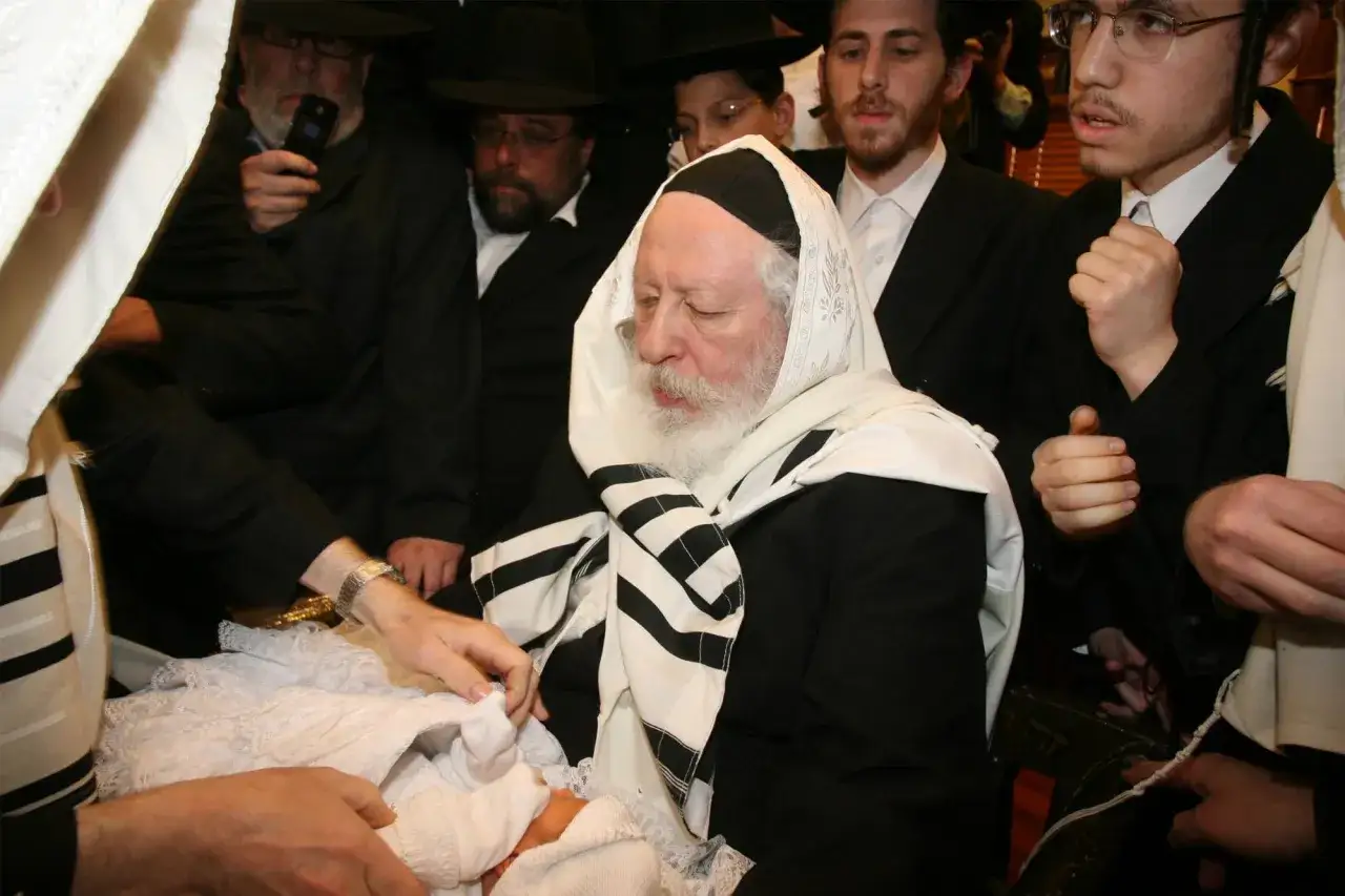 Cérémonie de fete juive circoncision. Un bébé est entouré d'hommes en tenue traditionnelle, certains portant des chapeaux noirs.