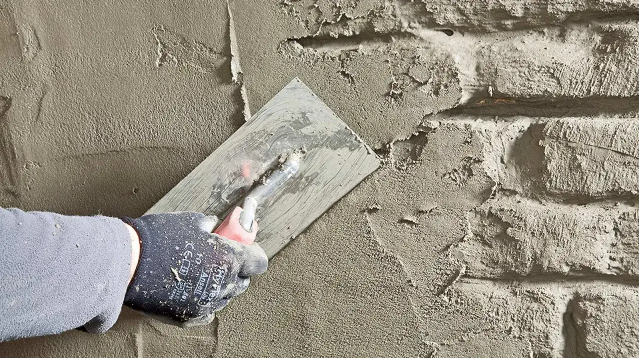 Hand mit Handschuh verputzt Wand f&uuml;r keller trockenlegen von innen selber machen.