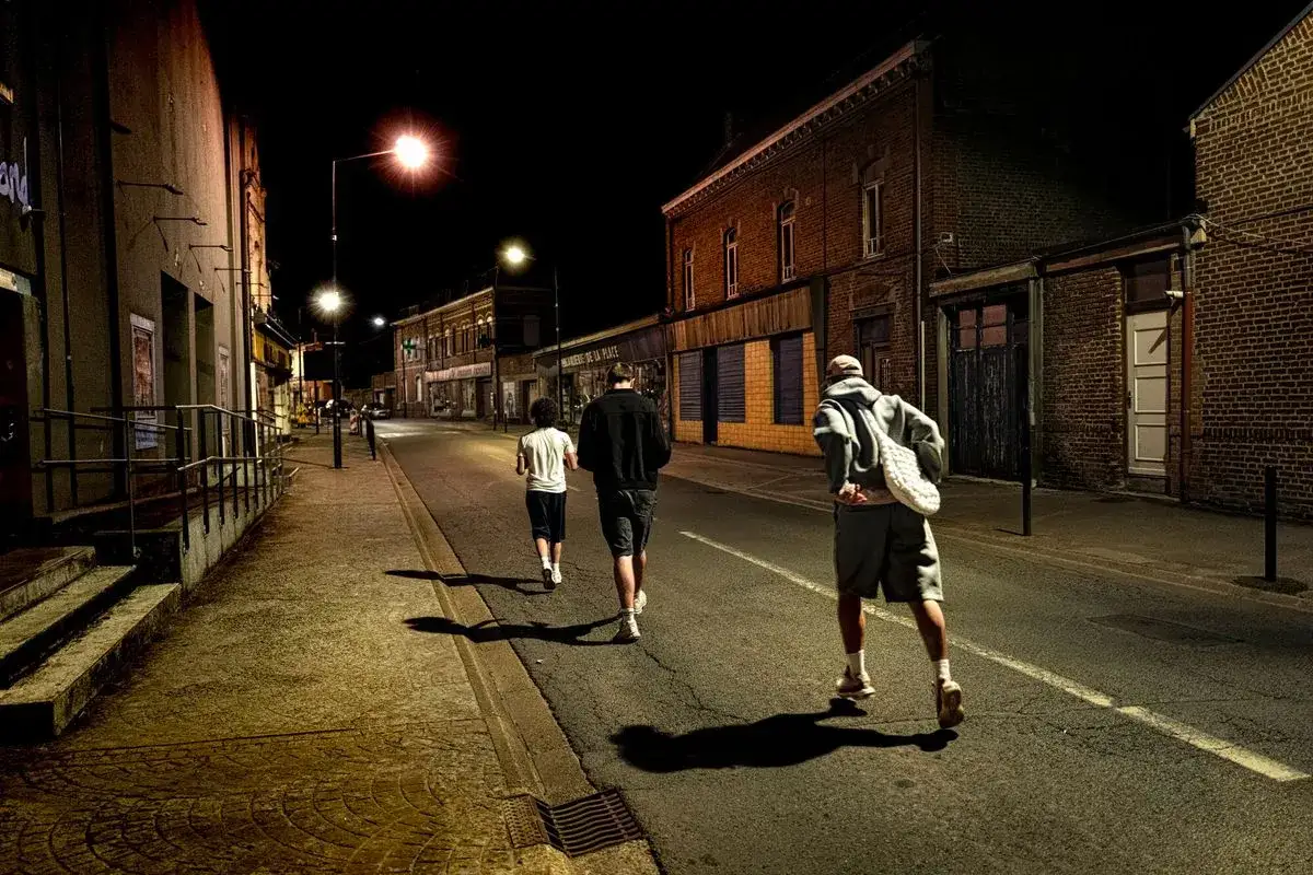 Trois silhouettes marchent dans une rue déserte la nuit. Un jeune homme court devant, suivi par deux autres. Le **mineur dehors la nuit** semble être le plus jeune des trois.