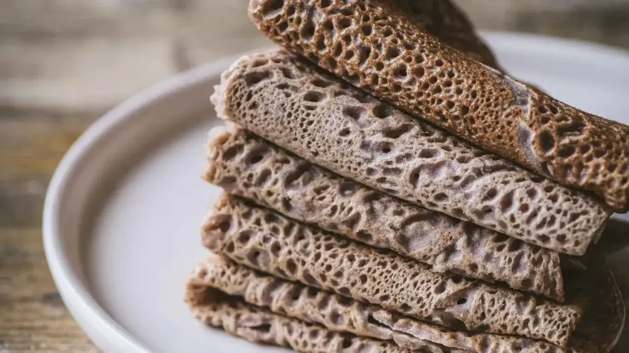 Pile de crêpes fines et trouées, typiques des spécialités culinaires de Bretagne.