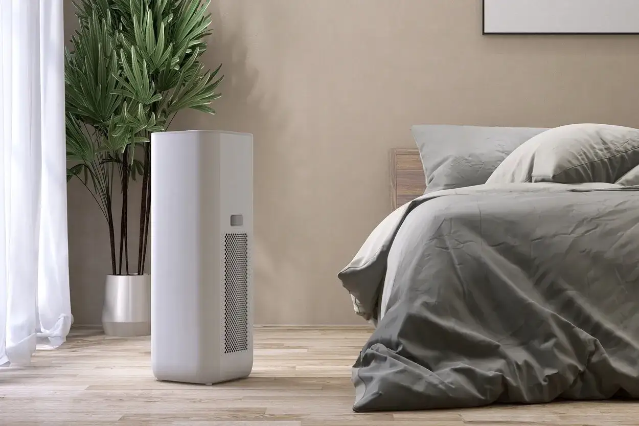 Un deumidificatore di notte, silenzioso e discreto, accanto a un letto confortevole e una pianta verde.