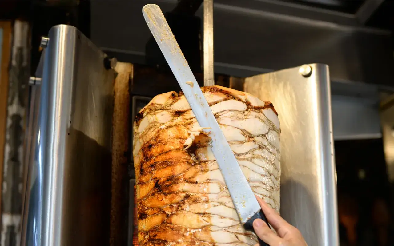 Oto co to jest kula mocy w kebabie: soczysty, obracający się mięsny walec, z którego ostry nóż ścina idealne kawałki do pysznego dania.