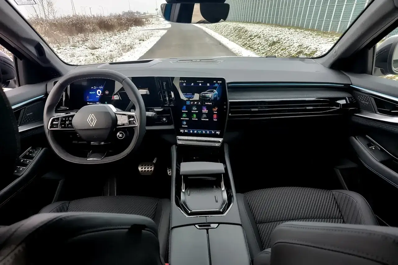Wnętrze nowego austral renault z dużym ekranem multimedialnym i cyfrowymi zegarami. Widok z miejsca kierowcy na drogę.