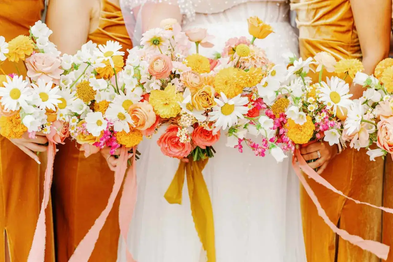 Wesele w kolorach słońca: bukiety druhen z r&oacute;żnymi rodzajami wstążek florystycznych, w tym jedwabnymi i tiulowymi, tworzą romantyczną całość.
