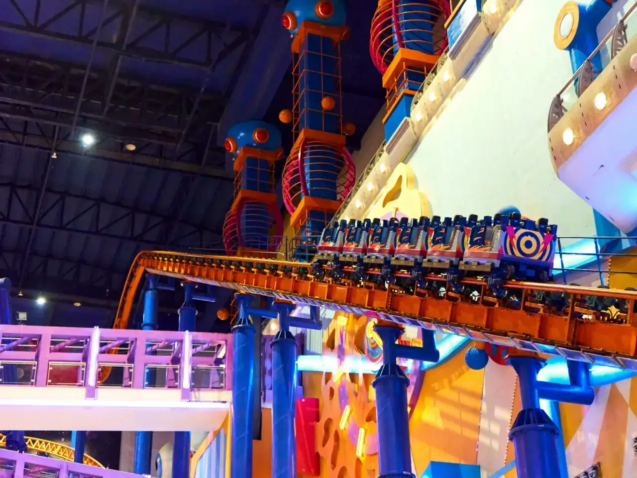 Pociąg z kolorowymi wagonikami na torach największego rollercoastera w Polsce.