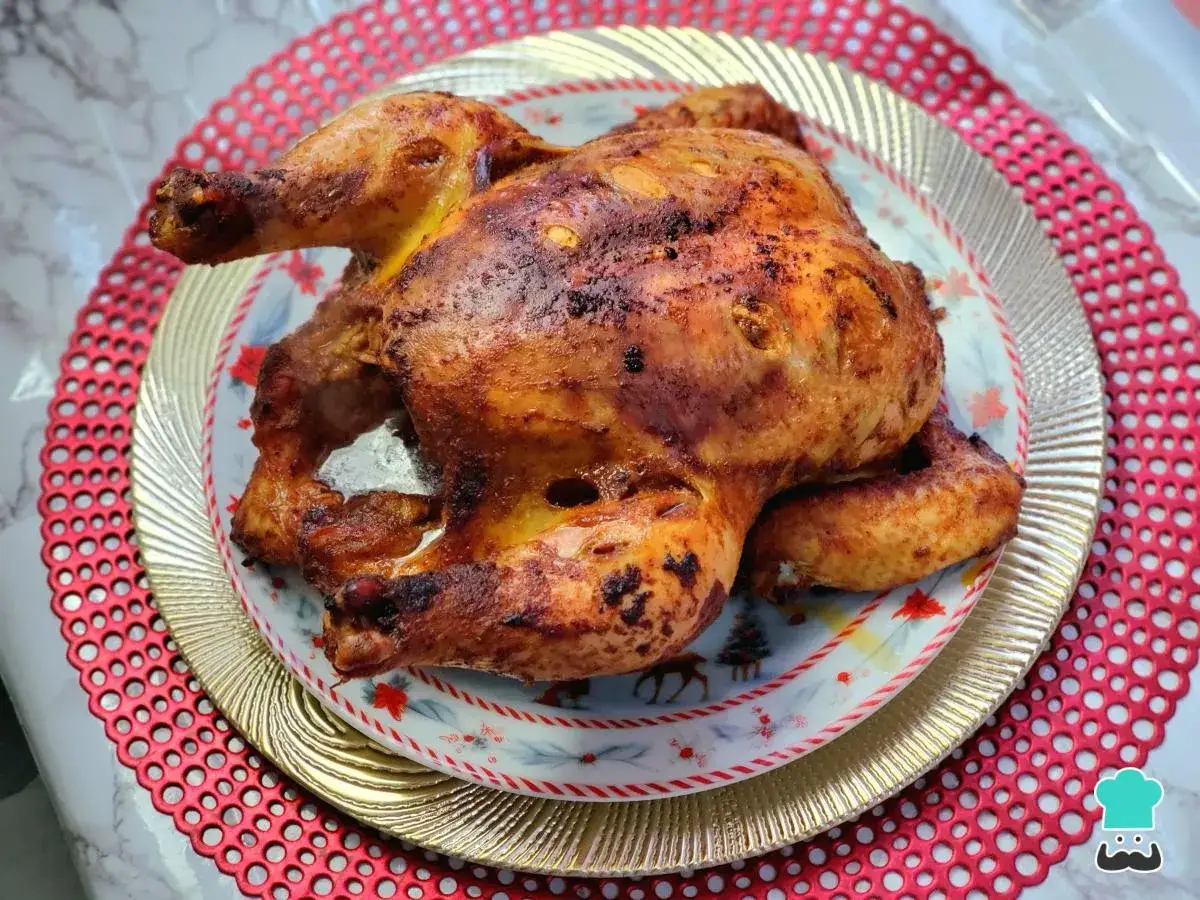 Un jugoso pollo a la brasa, dorado y crujiente, servido en un plato festivo.