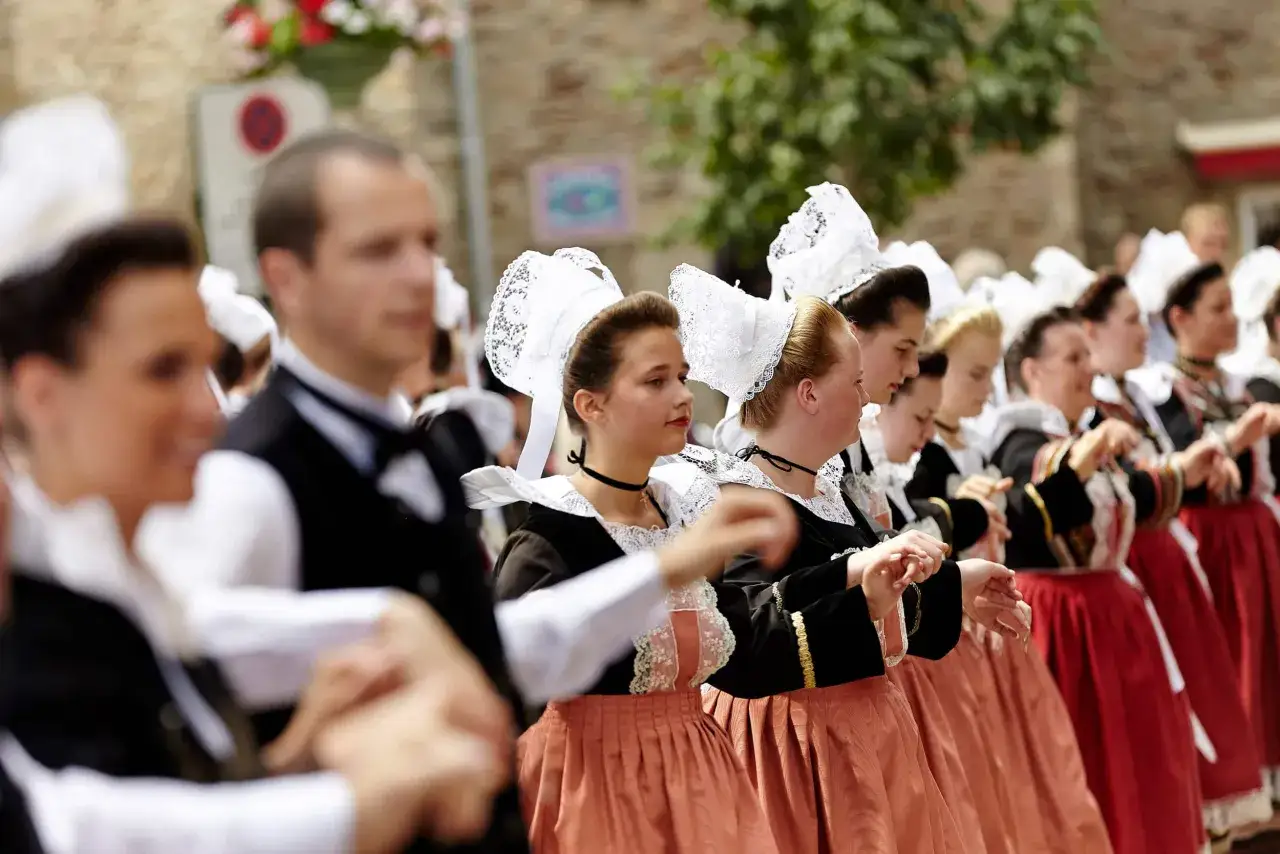 Gente con trajes tradicionales bretones en Francia, con sus caracter&iacute;sticos tocados blancos y faldas amplias.