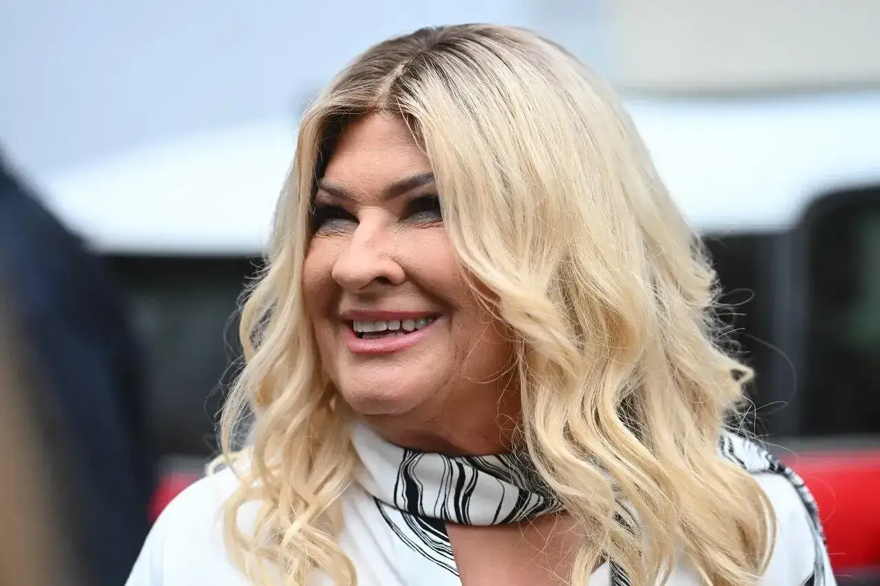 Beata Kozidrak bez peruki, z falowanymi blond włosami i charakterystycznym makijażem, uśmiecha się.