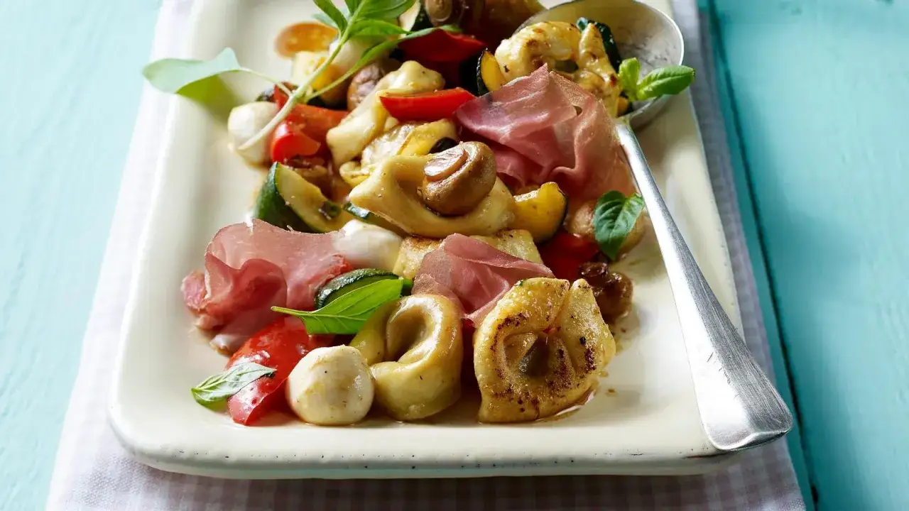 Ein k&ouml;stlicher Tortellini-Salat mit Rucola, Mozzarella, Tomaten, Zucchini und Schinken.