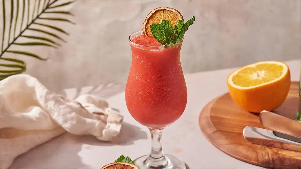 En frostig strawberry daiquiri med mynta och torkad apelsin, redo att avnjutas.