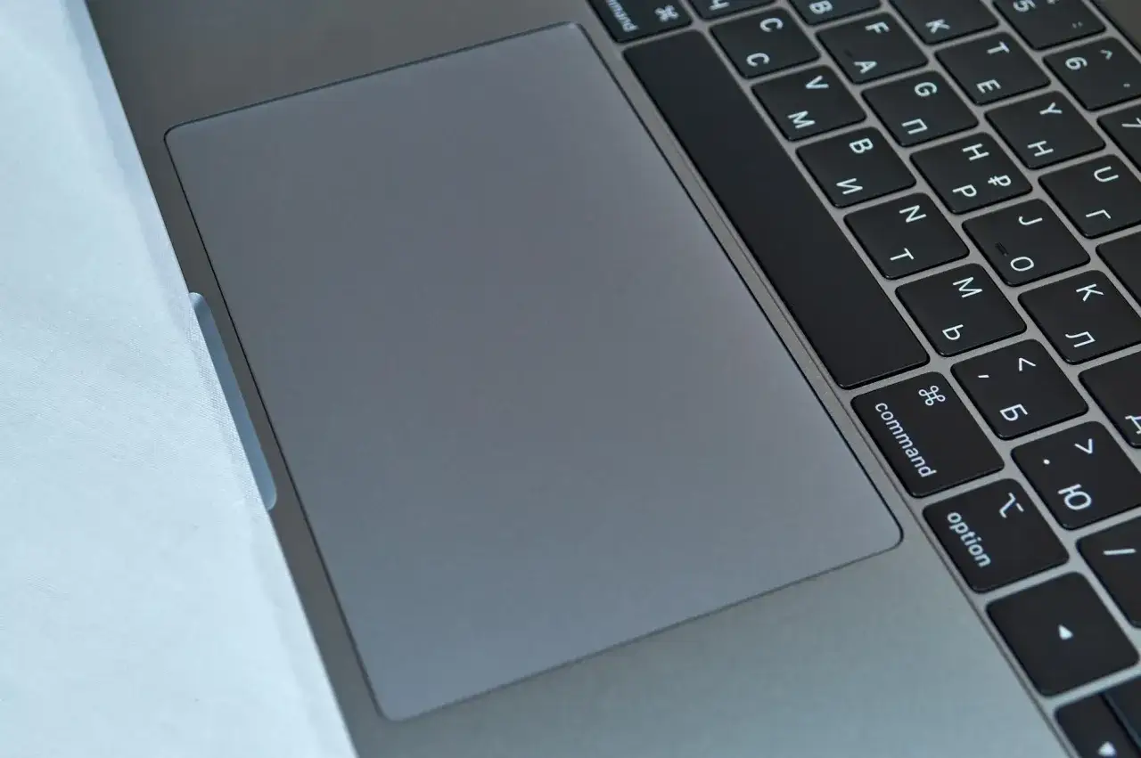 Szary touchpad laptopa obok klawiatury z klawiszem 