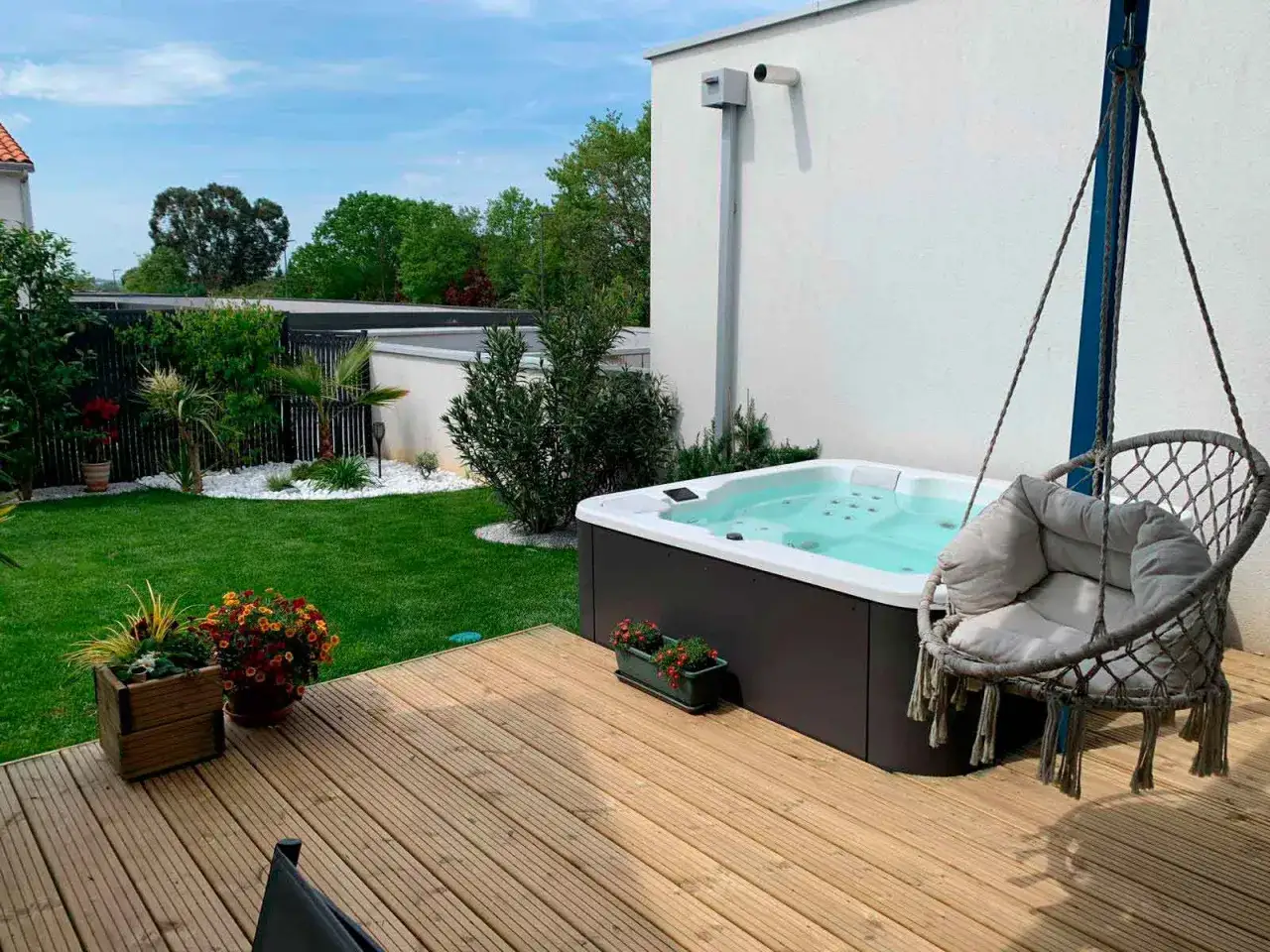 Un jacuzzi prêt pour un traitement spa relaxant, avec un fauteuil suspendu invitant à la détente dans un jardin verdoyant.