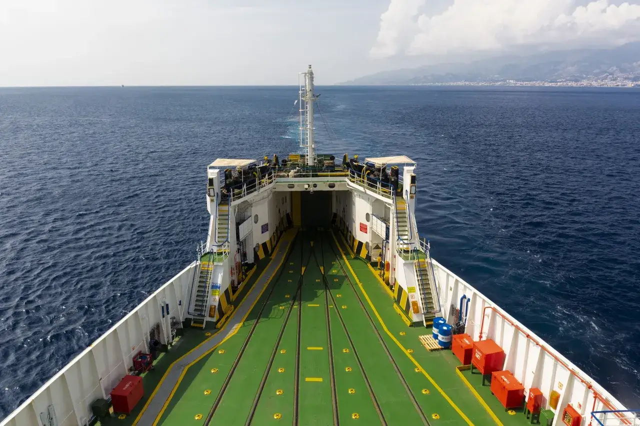 The ferry's open car deck awaits vehicles ready to drive to Sicily. The deep blue sea stretches to the horizon.