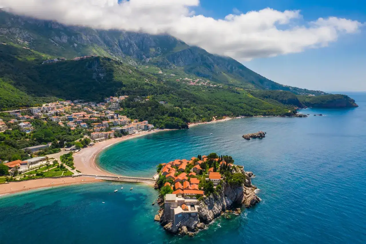 Wyspa Sveti Stefan, klejnot Czarnog&oacute;ry, z malowniczą plażą i g&oacute;rami w tle. Czy to Chorwacja czy Czarnog&oacute;ra? To zdecydowanie Czarnog&oacute;ra!