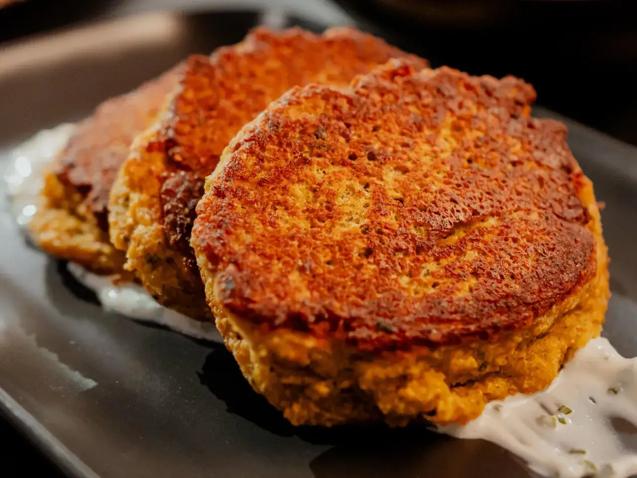 Trois galettes dorées, comme des tortillas pois chiche, reposent sur une sauce blanche crémeuse.