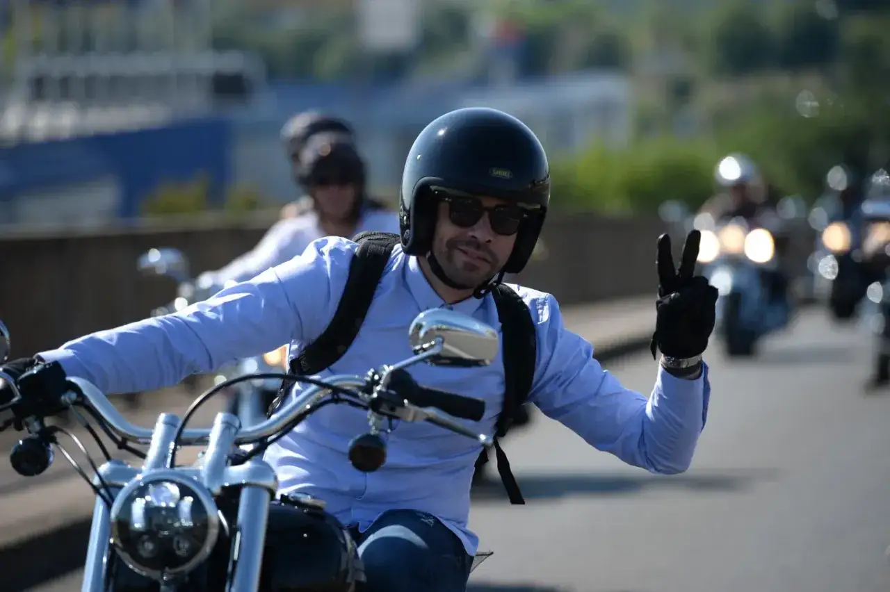 Motocyklista w kasku i okularach pozdrawia gestem 